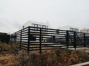 a black and white building sitting on top of a dry grass field